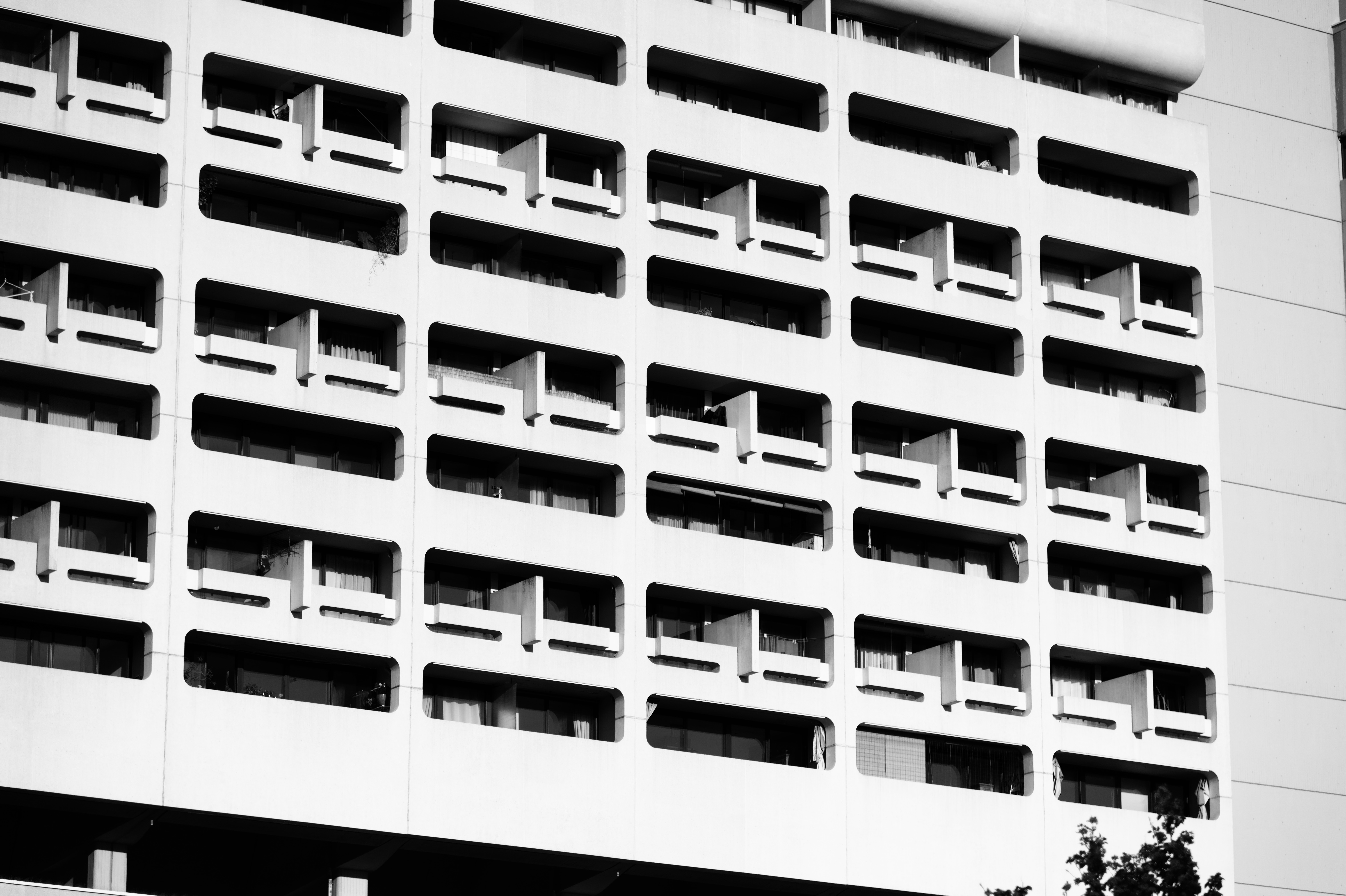 Rhythmic grid of recessed balconies creating pattern of light and shadow