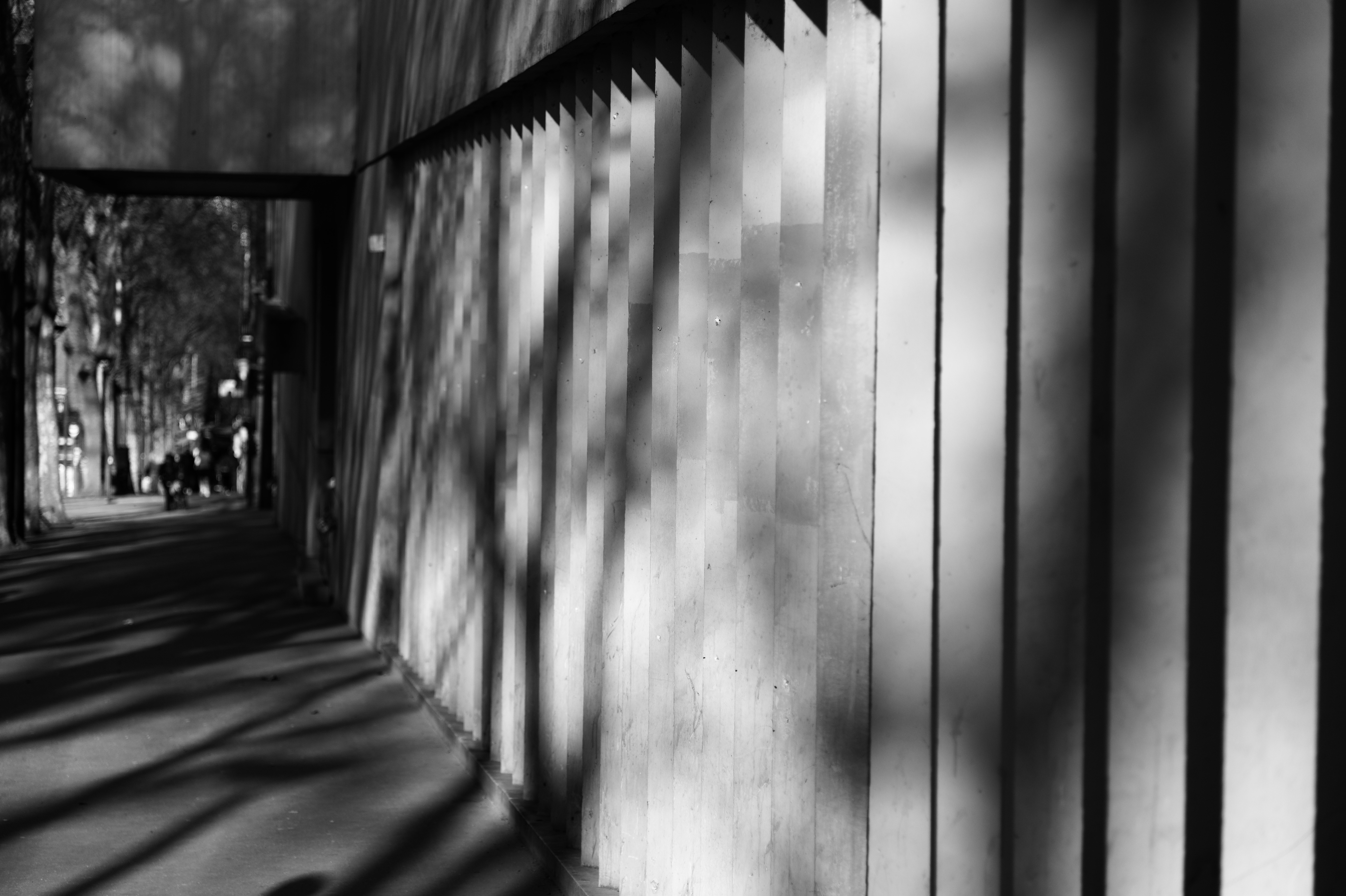 Concrete colonnade with repeating pillars casting striped shadows